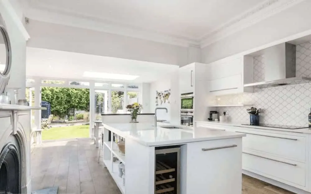 A kitchen with a stove, oven, sink and a clock.