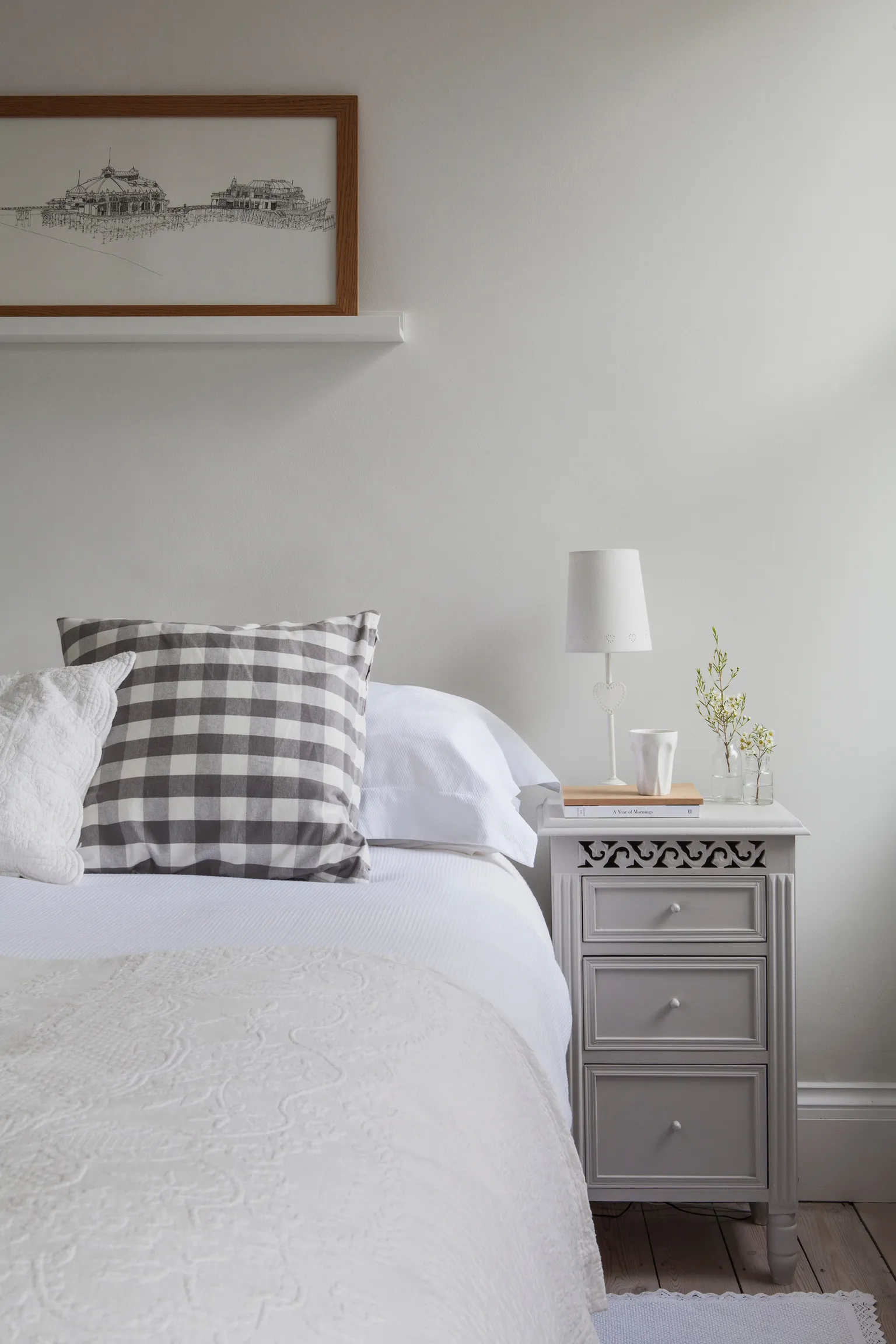 A bedroom with a bed, nightstand, and picture on the wall.