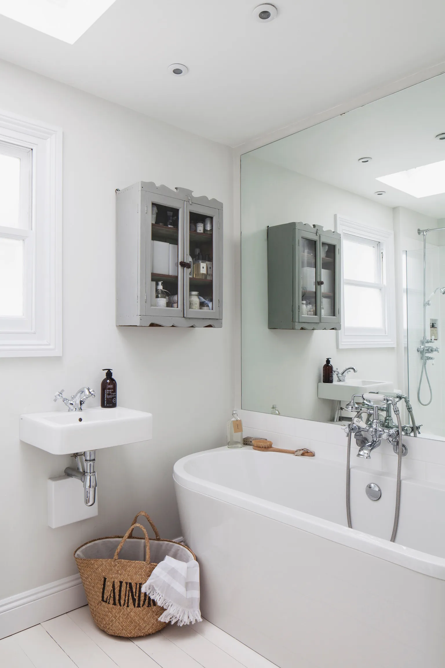 A bathroom with a tub, sink, and mirror.